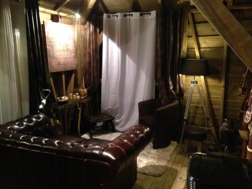 a living room with a leather couch and a curtain at West Indies Cottage in Pointe-Noire