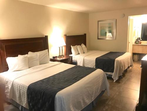 a hotel room with two beds and a window at At Home Inn - Fort Pierce in Fort Pierce