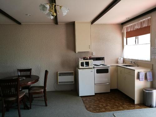 a small kitchen with a table and a microwave at Hacienda Motel in Invercargill