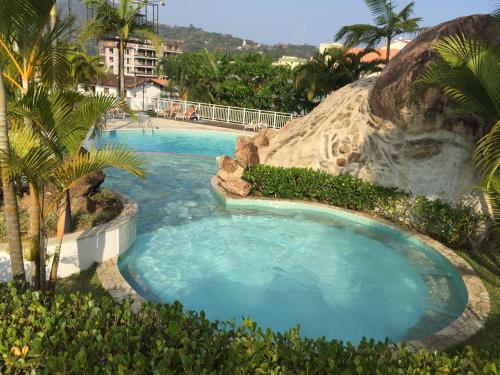 a large swimming pool in a resort with palm trees at UBATUBA, APARTAMENTO TOP in Ubatuba