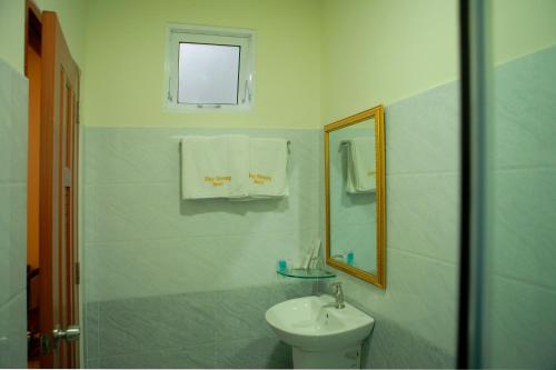 een witte badkamer met een wastafel en een spiegel bij Huy Hoang 1 Hotel in Ho Chi Minh-stad