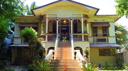 une grande maison jaune avec des escaliers en face de celle-ci dans l'établissement Oasis Balili Heritage Lodge, à Tagbilaran