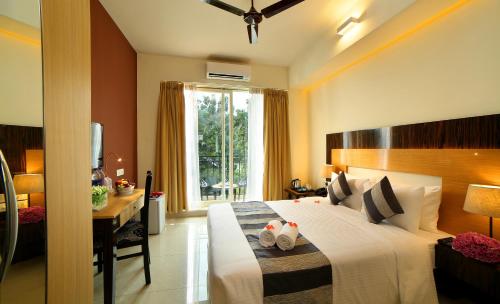 Schlafzimmer mit einem Bett, einem Schreibtisch und einem Fenster in der Unterkunft Casa Rio Resorts Athirappilly in Athirappilly