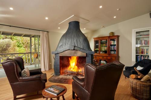 a fireplace in a living room with two chairs at Awaroa Lodge in Awa-iti