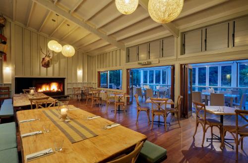 a dining room with tables and chairs and a fireplace at Awaroa Lodge in Awa-iti