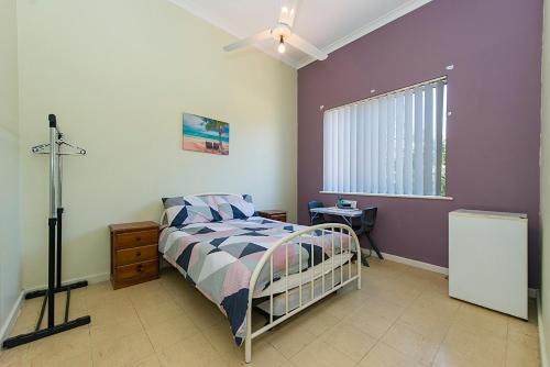 a bedroom with a bed and a purple wall at Victoria Park Lodge in Perth