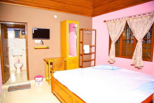 a bedroom with a bed and a tv and a bathroom at Mom&Pop Thyparambil Heritage in Alleppey
