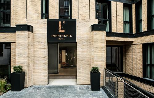 a brick building with a sign for theinemite clinic at L'Imprimerie Hôtel in Clichy