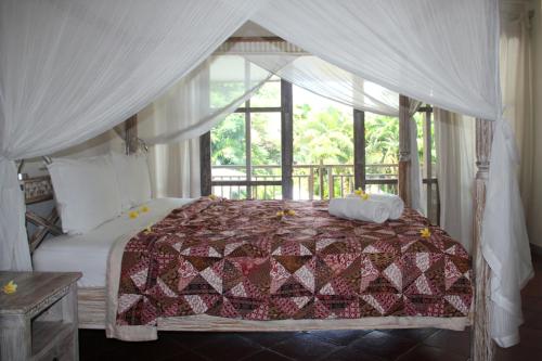 a bedroom with a bed with a canopy at Papaya Guesthouse in Canggu