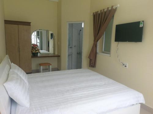 1 dormitorio con cama blanca y espejo en ST. Dong Tam Guesthouse en Dalat