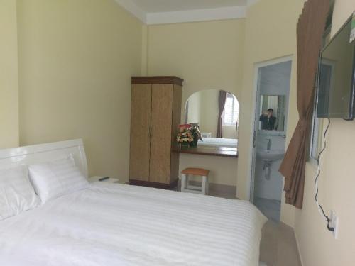 ein Schlafzimmer mit einem Bett und ein Badezimmer mit einem Spiegel in der Unterkunft ST. Dong Tam Guesthouse in Da Lat