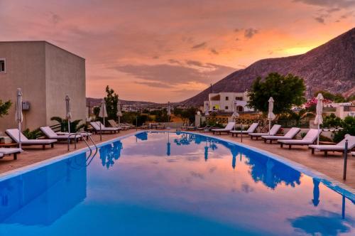 einen Pool in einem Resort mit Stühlen und Sonnenuntergang in der Unterkunft Phevos Villa in Perissa