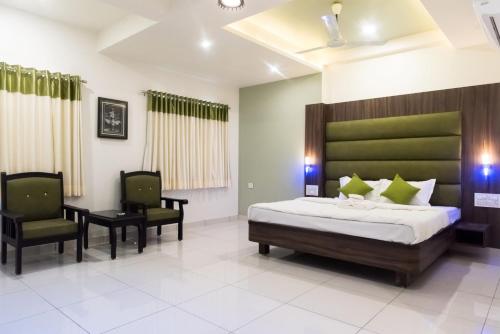 a bedroom with a bed and two chairs at Hotel Shyam Palace in Bhuj