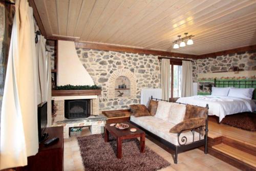 a living room with a bed and a couch and a fireplace at Efharis Filoxenon in Feneos