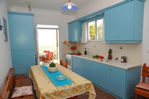 a kitchen with blue cabinets and a table in it at Fiore Hill Sea View Studios in Vasilikos