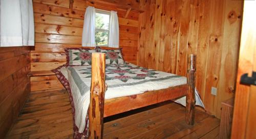 a bedroom with a bed in a log cabin at Robin Hill Camping Resort Deluxe Cottage 13 in Lenhartsville