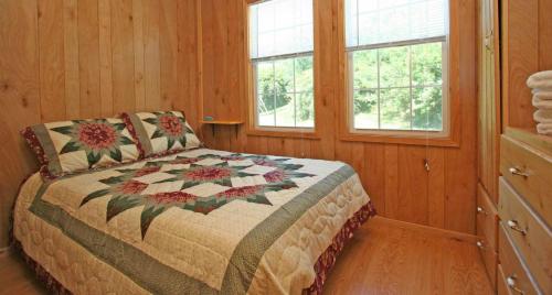 a bedroom with a bed and two windows at Robin Hill Camping Resort Premium Cottage 1 in Lenhartsville