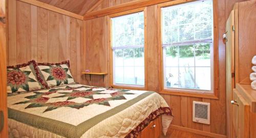 a bedroom with a bed and two windows at Robin Hill Camping Resort Premium Cottage 9 in Lenhartsville