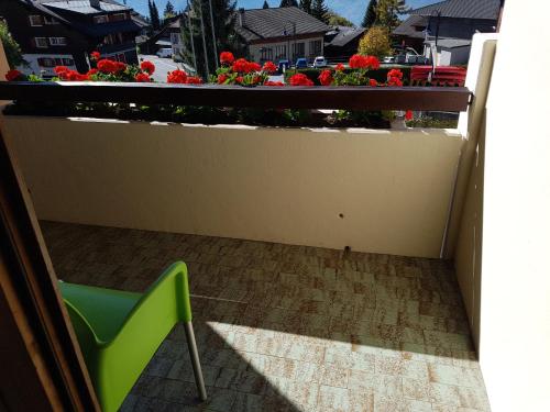 a green chair and a balcony with flowers at Résidence Panorama A201 in Villars-sur-Ollon
