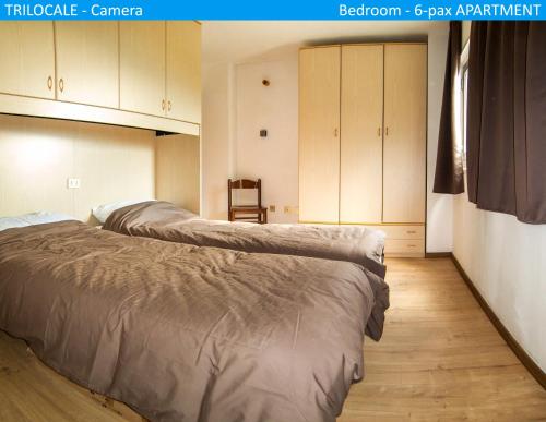 two beds in a room with a room with cabinets at Apartment Tonale in Passo del Tonale