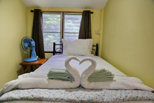 a bed with two towels in the shape of a heart at TP Hut Bungalows in Ko Chang