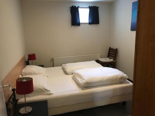 een slaapkamer met een bed met witte lakens en een raam bij de Goede Ree Huisje 1 en 2 - No Companies in Goedereede