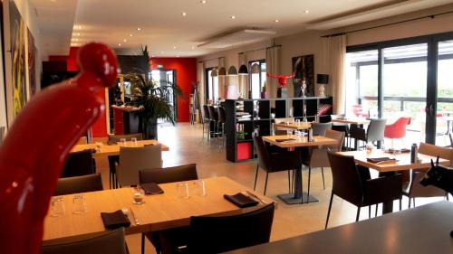 a restaurant with tables and chairs and a person in the foreground at Hotel-Restaurant Lann Roz / Côte Cuisine in Carnac