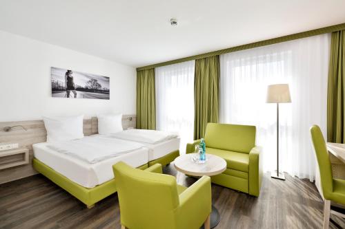 ヘルツォーゲンアウラッハにあるNovina Sleep Inn Herzogenaurachのベッド、テーブル、椅子が備わるホテルルームです。