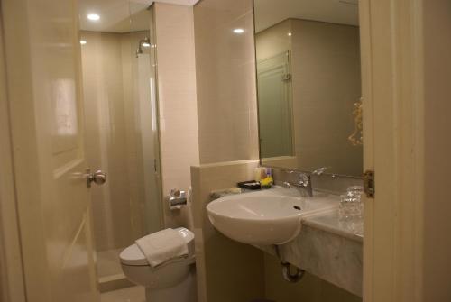 a bathroom with a sink and a toilet and a mirror at Grand Tropic Suites Hotel in Jakarta