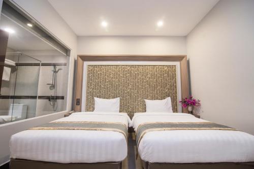 two beds in a room with a shower at New York Hotel in Phnom Penh