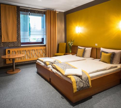 1 dormitorio con 1 cama grande y pared amarilla en Hotel Restauracja Tawerna Gliwice, en Gliwice