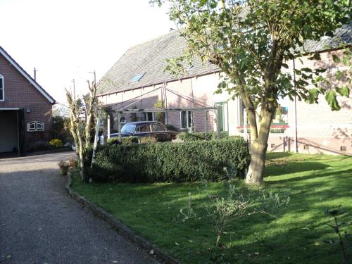 a house with a car parked in the yard at B&B De Kaagse Koe in Huigsloot