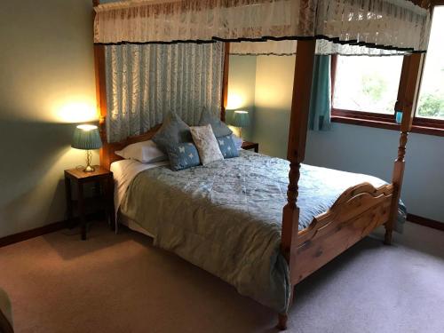 ein Schlafzimmer mit einem Himmelbett und einem Fenster in der Unterkunft Drumbuie Farm B&B in Drumnadrochit