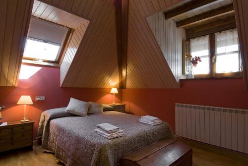 a bedroom with a bed with two lamps and two windows at Casa Rural Marín in Hecho