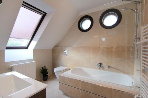a bathroom with a tub and a toilet and two windows at Good Luck Apartment in Hévíz