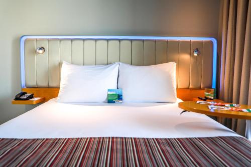 a bed with white pillows and a blue head board at Park Inn by Radisson Abu Dhabi Yas Island in Abu Dhabi