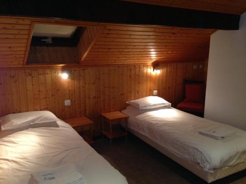 Cette chambre comprend deux lits et un fauteuil rouge. dans l'établissement Chalet Peloton, à La Chapelle-dʼAbondance