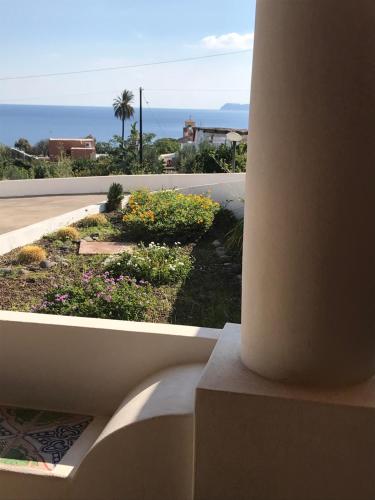 a balcony with a view of a garden and the ocean at Salina Case Vacanze in Santa Marina Salina