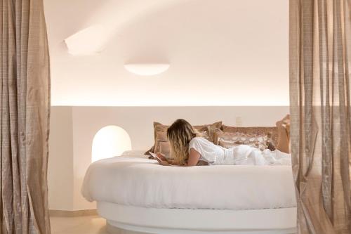 una mujer sentada encima de una cama en Amber Light Villas en Imerovigli