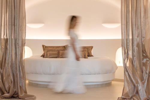 a person is standing in front of a bed at Amber Light Villas in Imerovigli