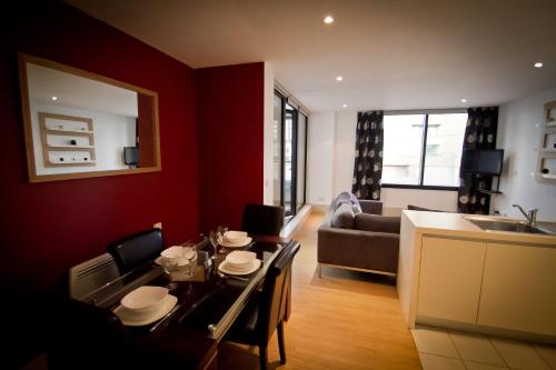 a living room with a dining table and a kitchen at Merchant Quarters Apartments in Liverpool