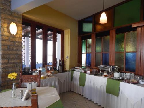 ハニア・タウンにあるPosidonio Hotelの白いテーブルクロスのテーブル2台付きレストラン