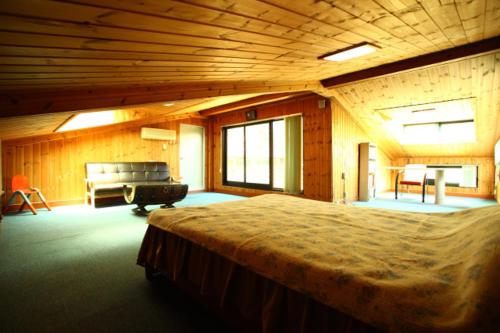 ein Schlafzimmer mit einem großen Bett in einem Holzzimmer in der Unterkunft Bluesky Pension in Pocheon-si