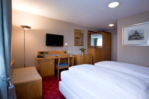 a hotel room with a bed and a desk with a television at Hotel Das Kleine Ritz in Fellbach