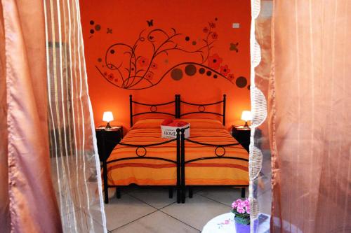 a bedroom with a bed with a orange wall at La Gardenia in Licodia Eubea