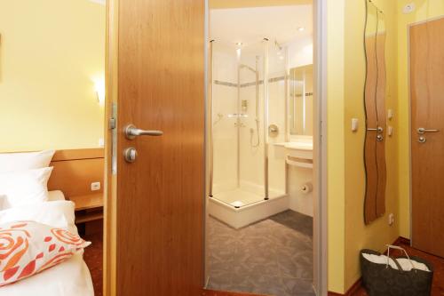 a bathroom with a shower and a toilet and a bed at BIO Hotel Bayerischer Wirt Augsburg in Augsburg