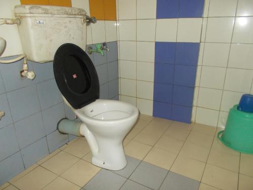 a bathroom with a toilet with a black seat at Hariprasadam in Guruvāyūr