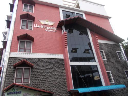 a red building with a sign on it at Hariprasadam in Guruvāyūr