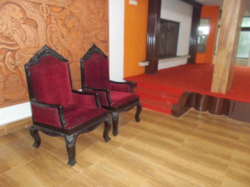 two red chairs in a room with a wooden floor at Hariprasadam in Guruvāyūr
