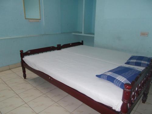a bedroom with a bed with white sheets and blue walls at Hariprasadam in Guruvāyūr